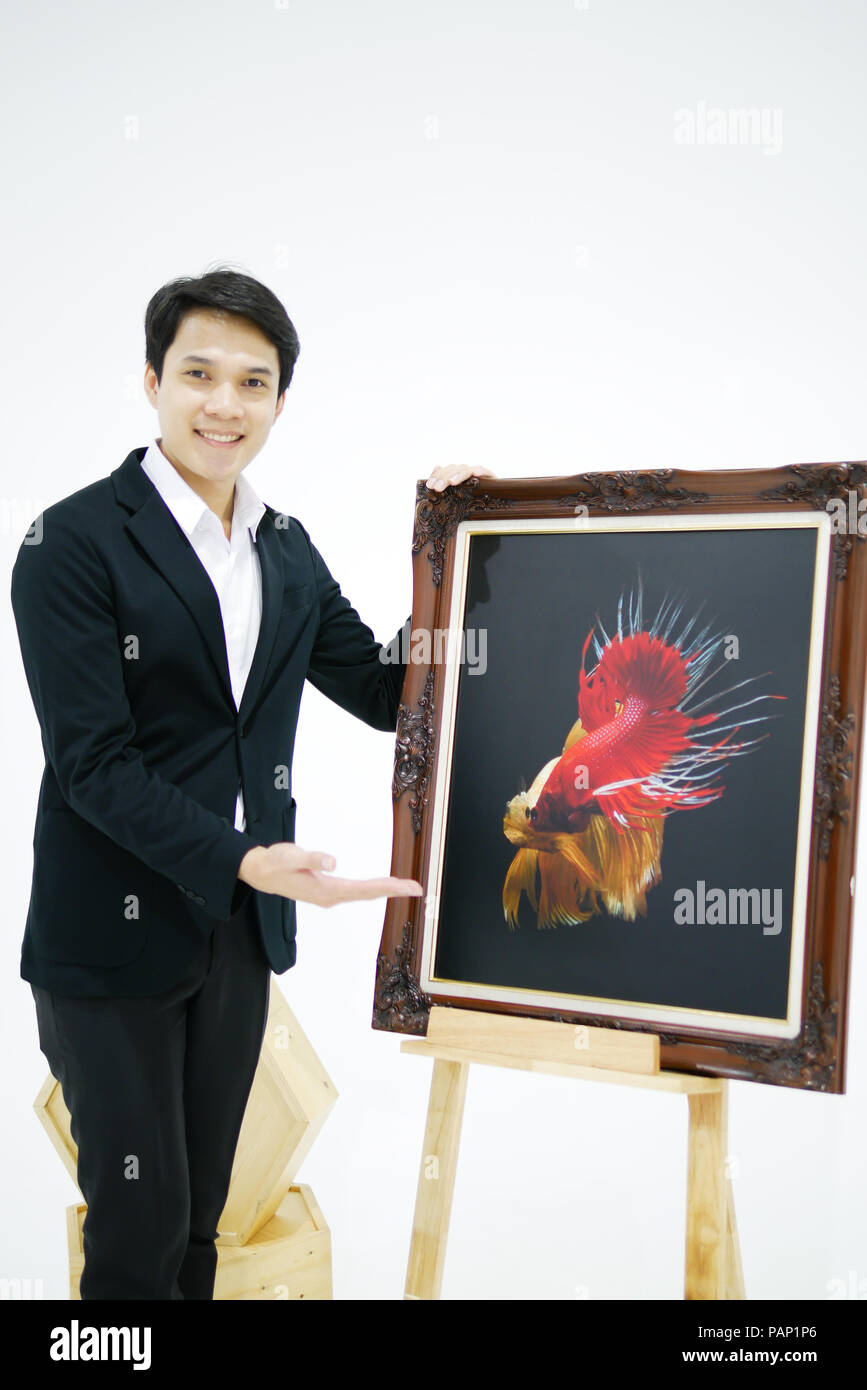 Smart Asian men is presenting the beautiful siamese fighting fish (betta) photo in the museum exhibition. Stock Photo