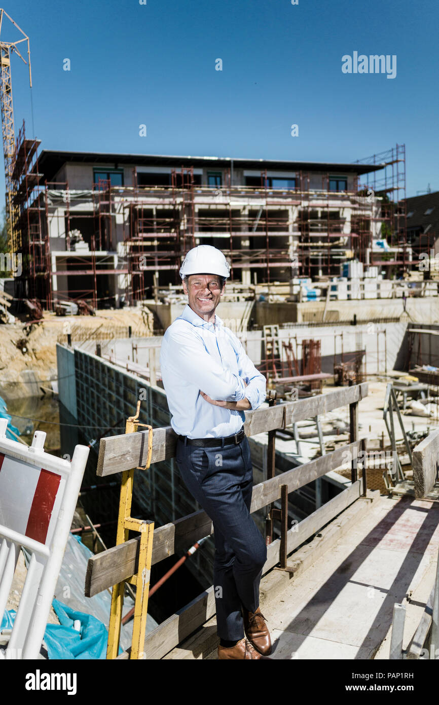 Portrait of smiling man wearing hard hat on construction site Stock Photo