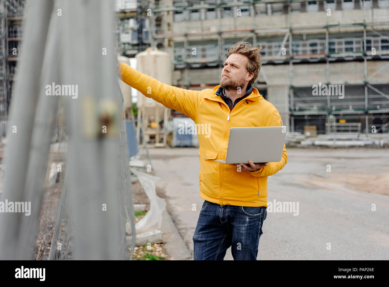Man holding laptop, construction site in the background Stock Photo