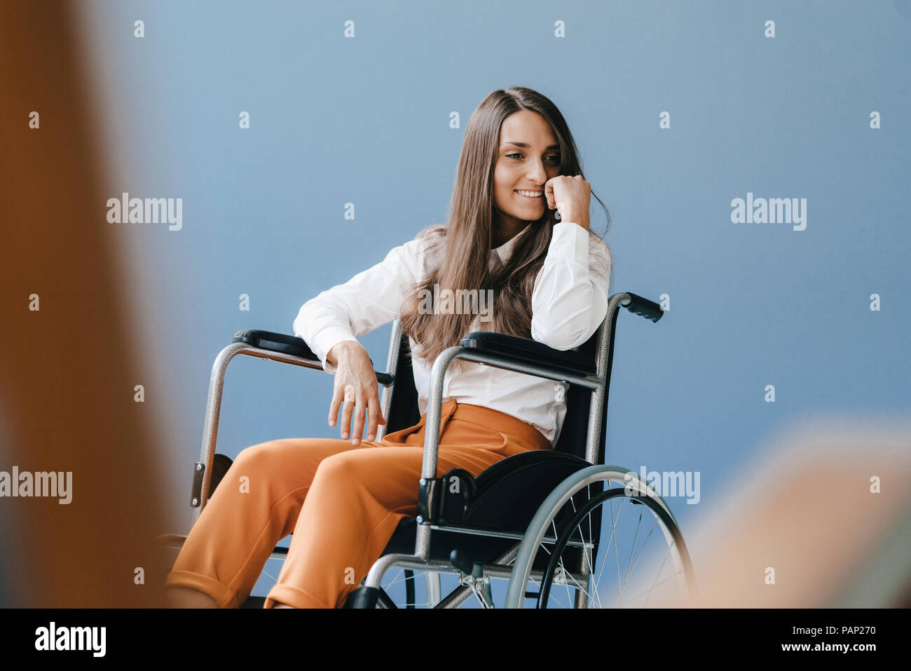 Young handicapped woman sitting in wheelchair, smiling Stock Photo