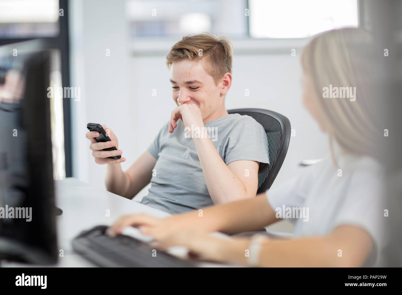 Students using cell phone and computer in class Stock Photo