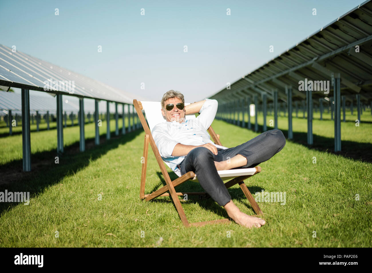 Mature man sitting in beach lounger, solar plant Stock Photo