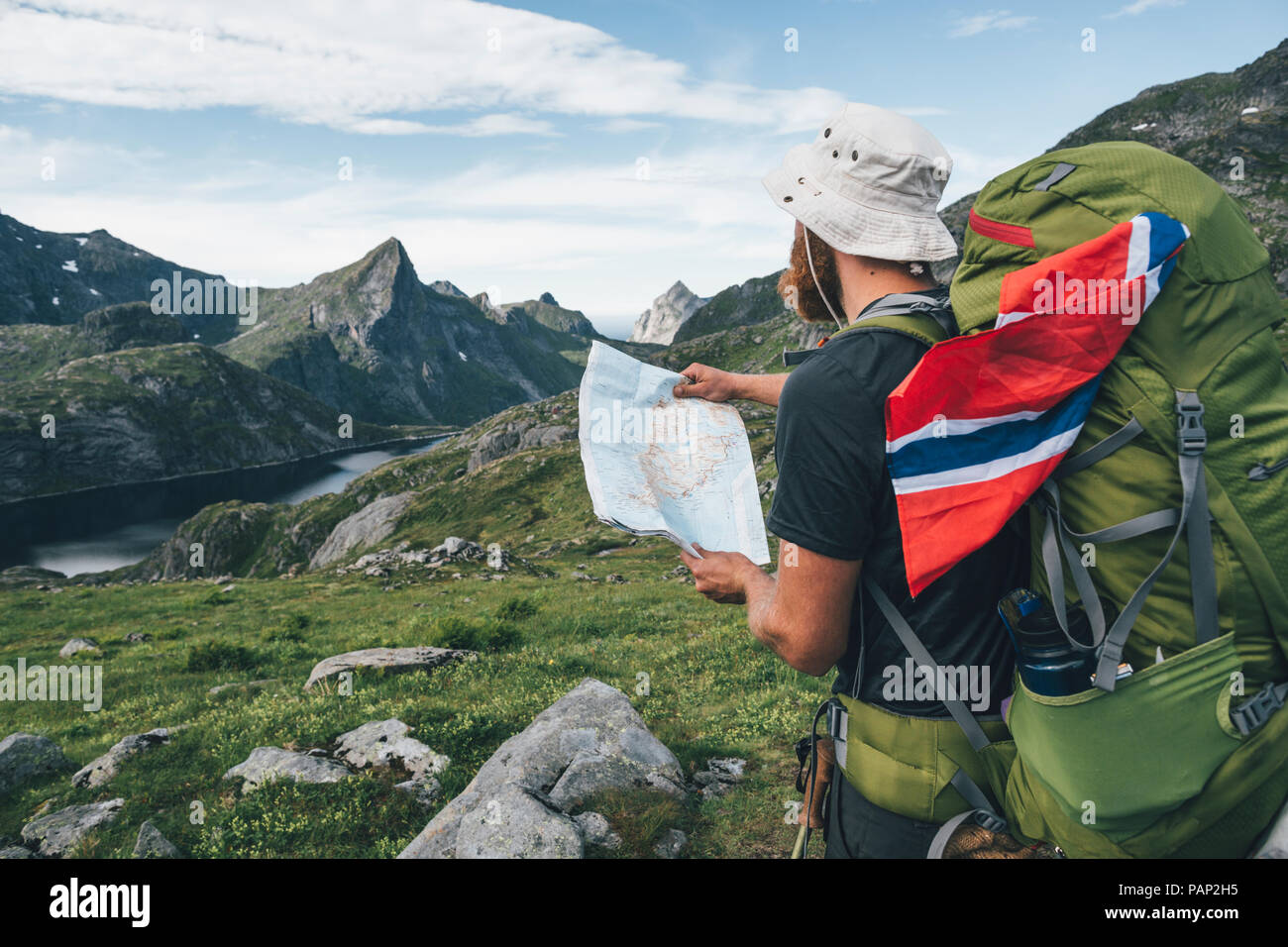Norway, Lofoten, Moskenesoy, Man with backpak and Norwegian flag holding map Stock Photo