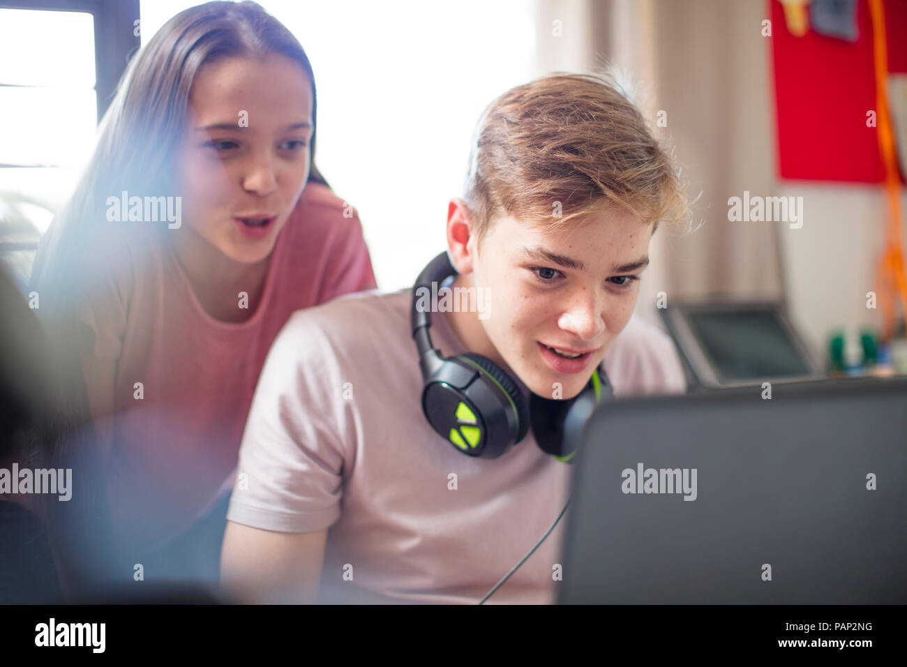 Teenage girl watching boy using laptop Stock Photo