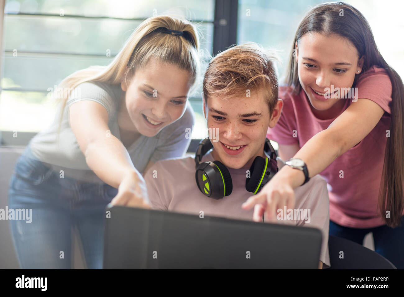 Teenage girls watching boy using laptop Stock Photo