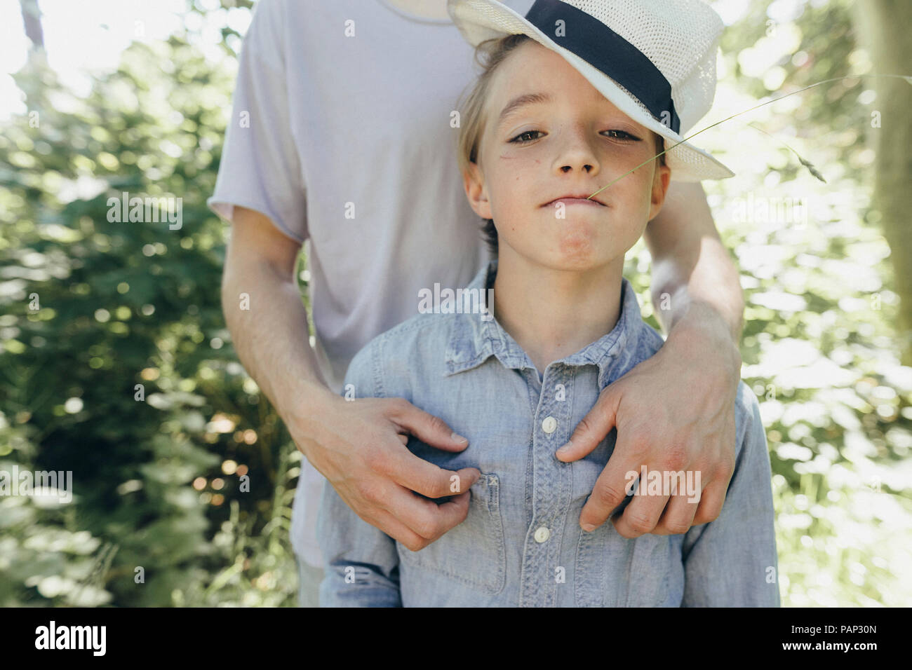 Portrait of boy wearing hat being embraced by a man Stock Photo