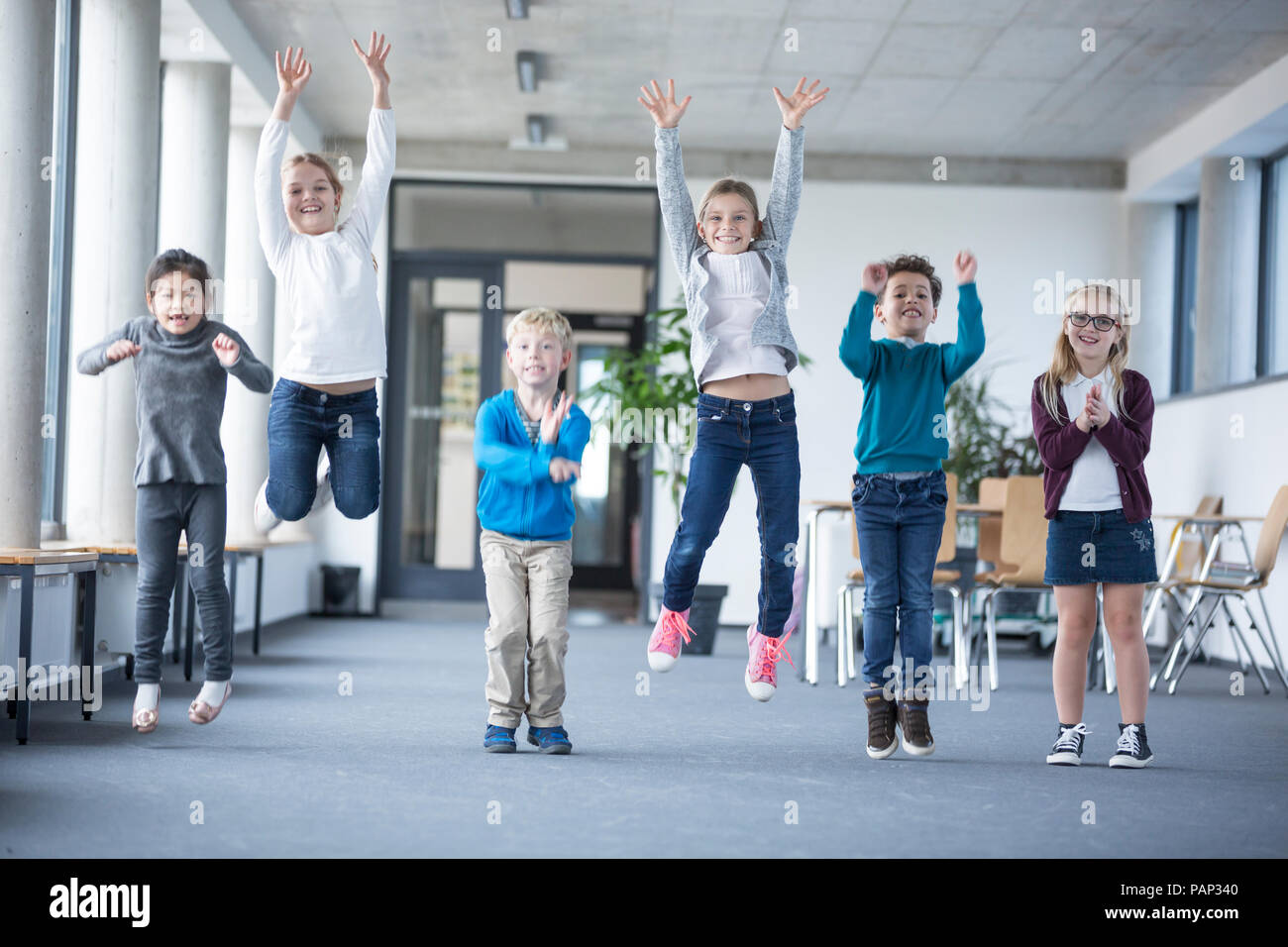 Excited pupils jumping on school corridor Stock Photo