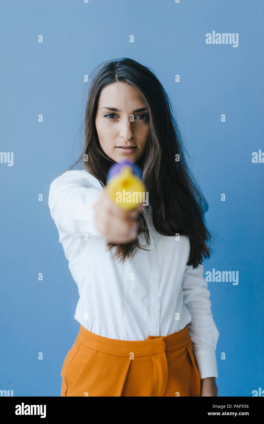 Pretty young woman shooting with a confetti gun Stock Photo