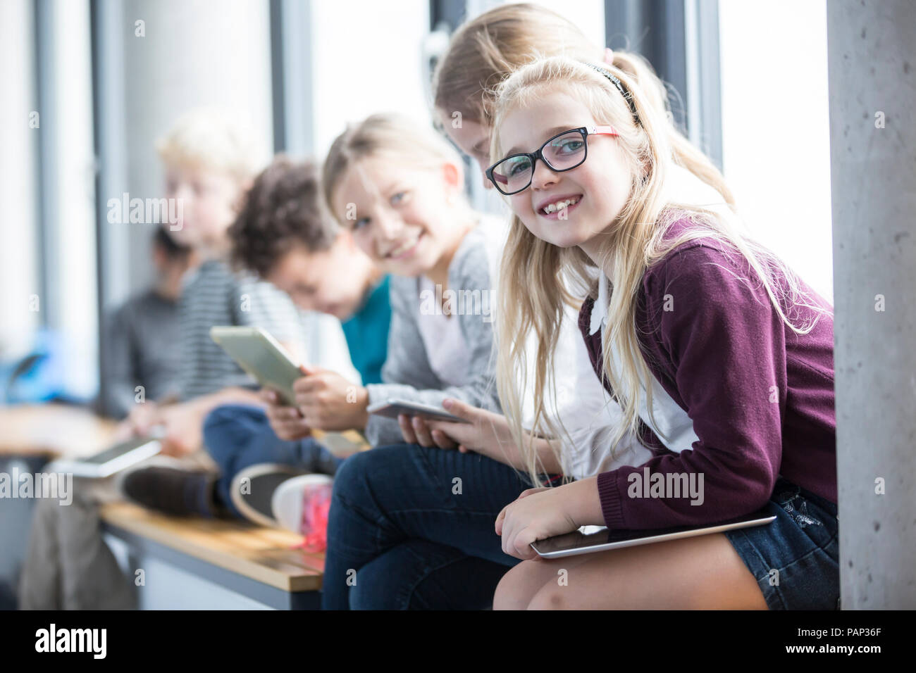 Smiling pupils with tablets on school corridor Stock Photo