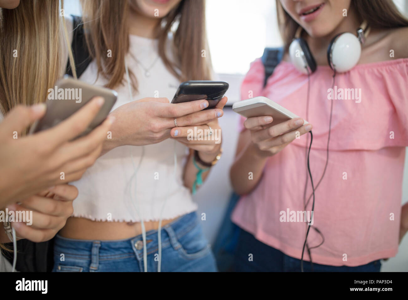 Teenage girls using cell phones in school Stock Photo