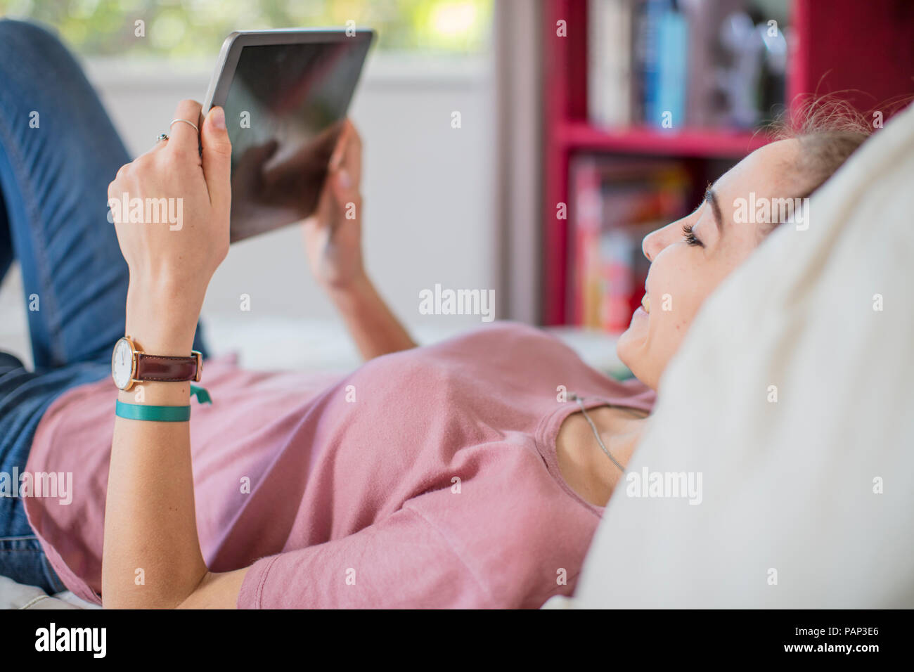 Teenage girl lying on bed looking at tablet Stock Photo