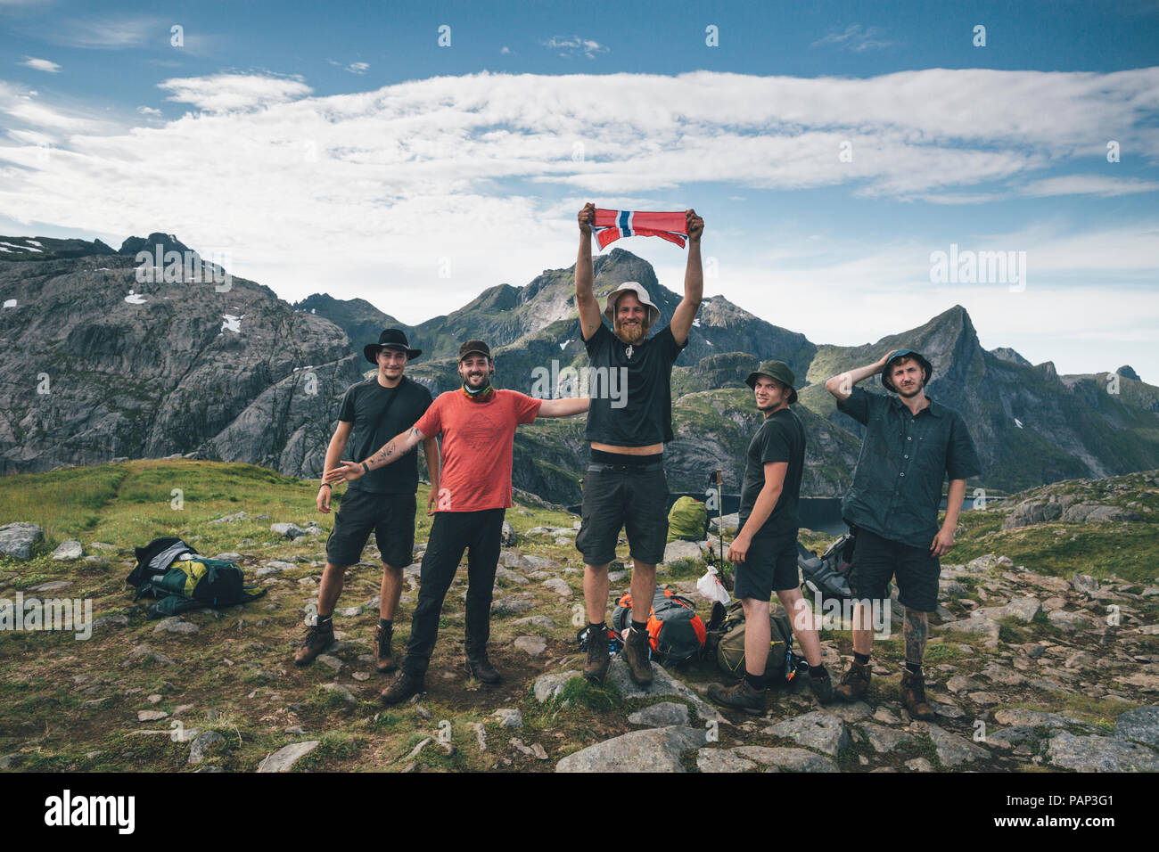 Norway, Lofoten, Moskenesoy, Group of young men cheering with Norwegian flag Stock Photo