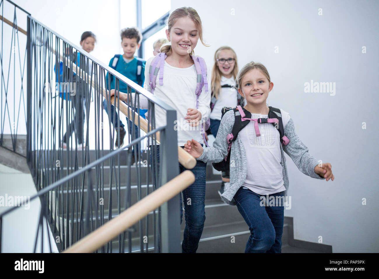 Happy pupils on staircase leaving school Stock Photo