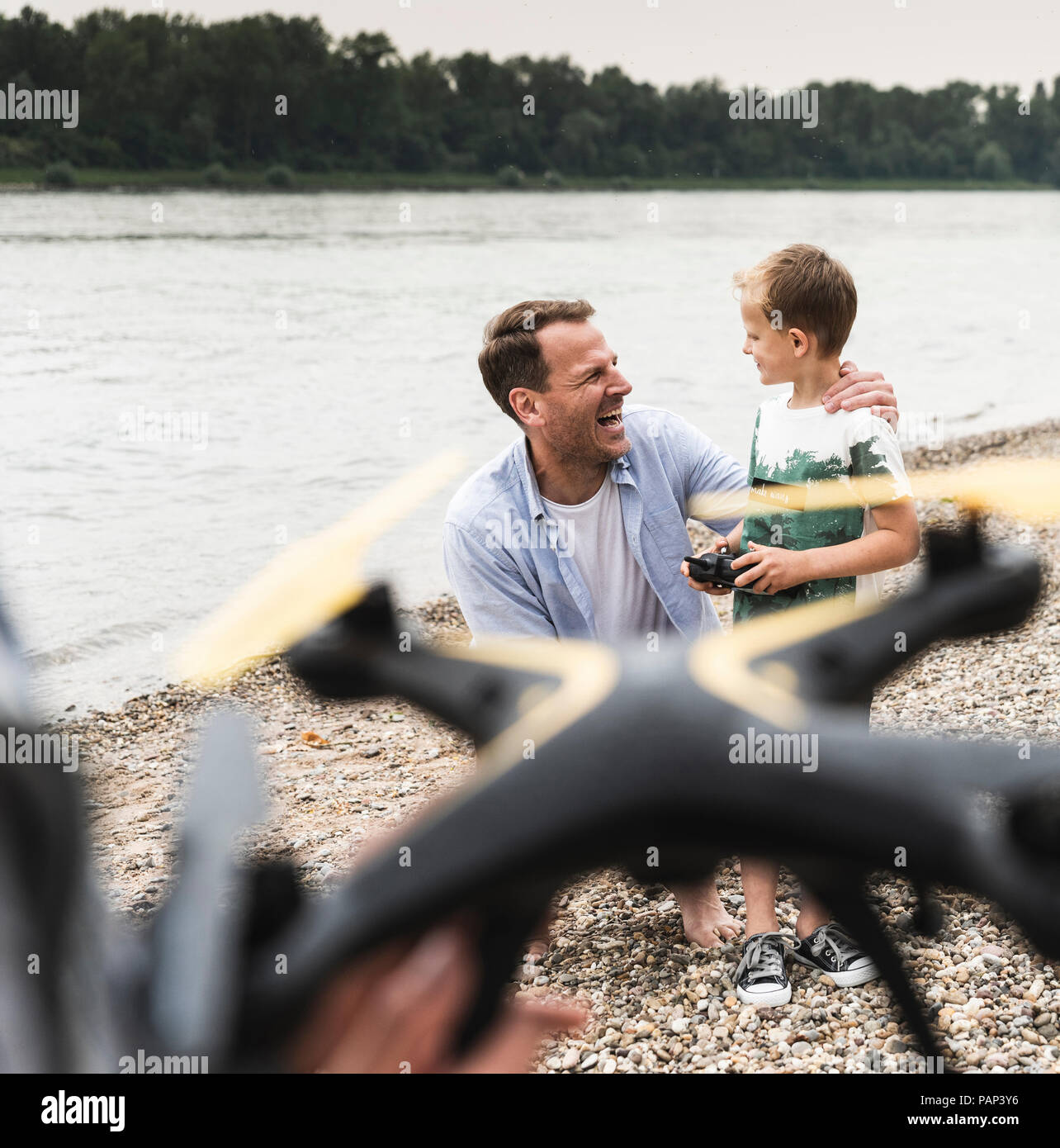 Happy father and son playing with drone at the riverside Stock Photo ...