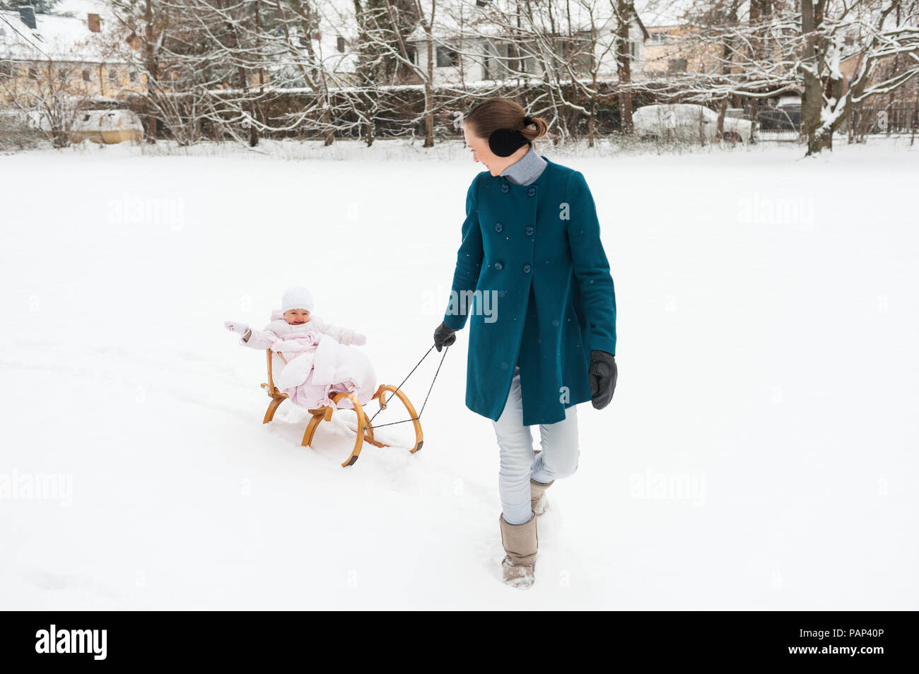 Mother pulling little daughter on sledge Stock Photo