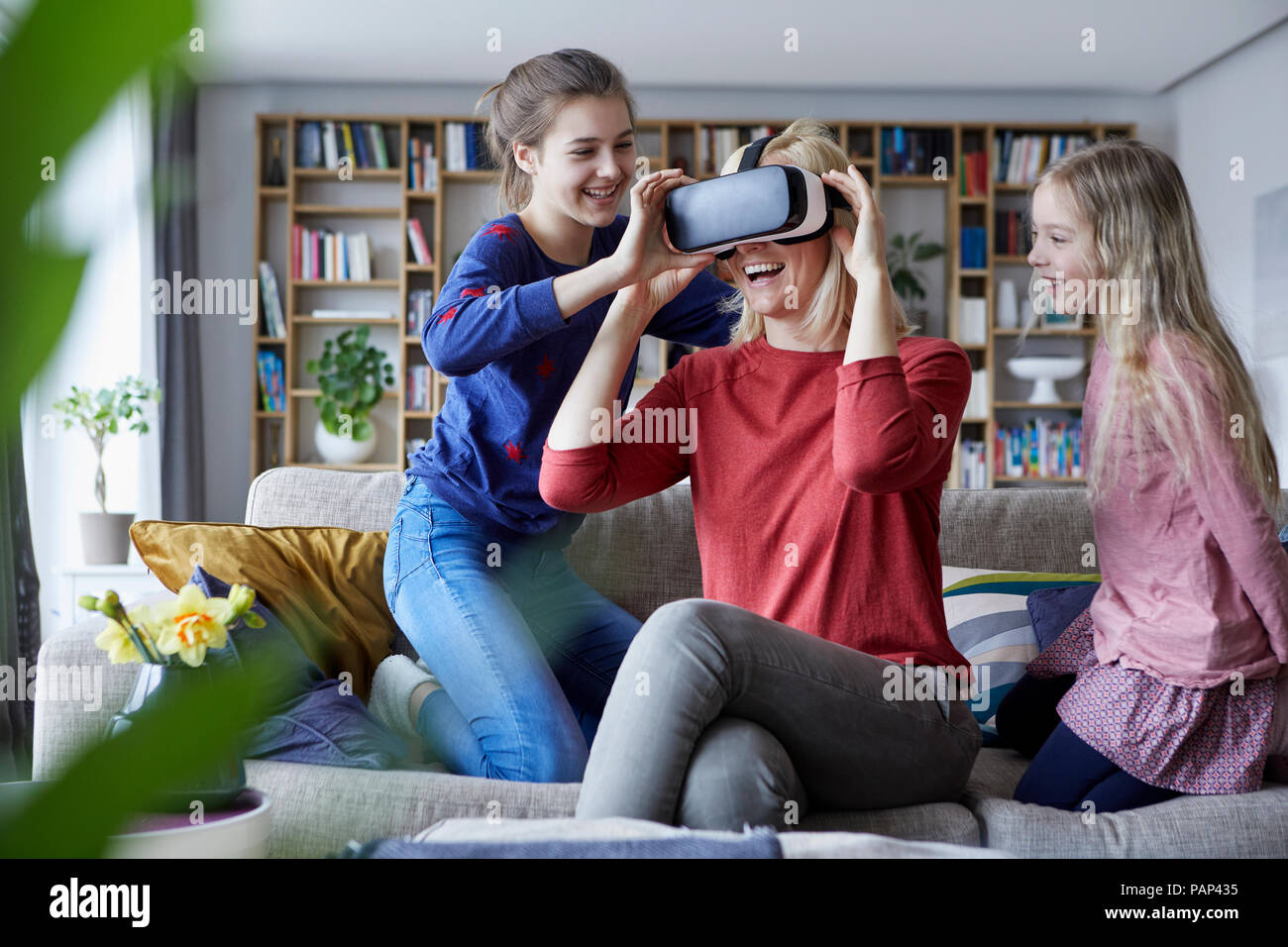 Daughters showing mother how to play with VR glasses Stock Photo