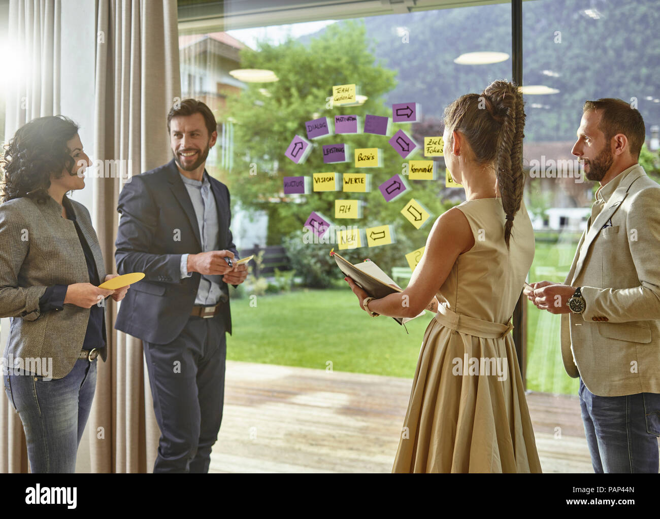 Colleagues discussing with sticky notes at the window Stock Photo