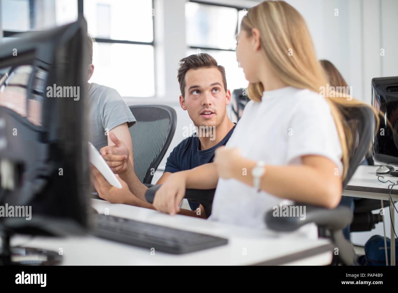 Teacher talking to student in computer class Stock Photo