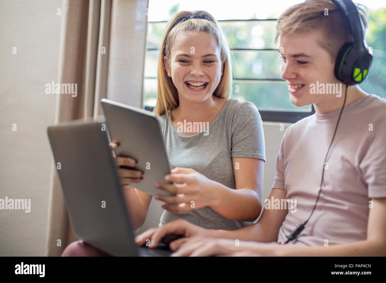 Happy boy and teenage girl with tablet, laptop and headphones Stock Photo