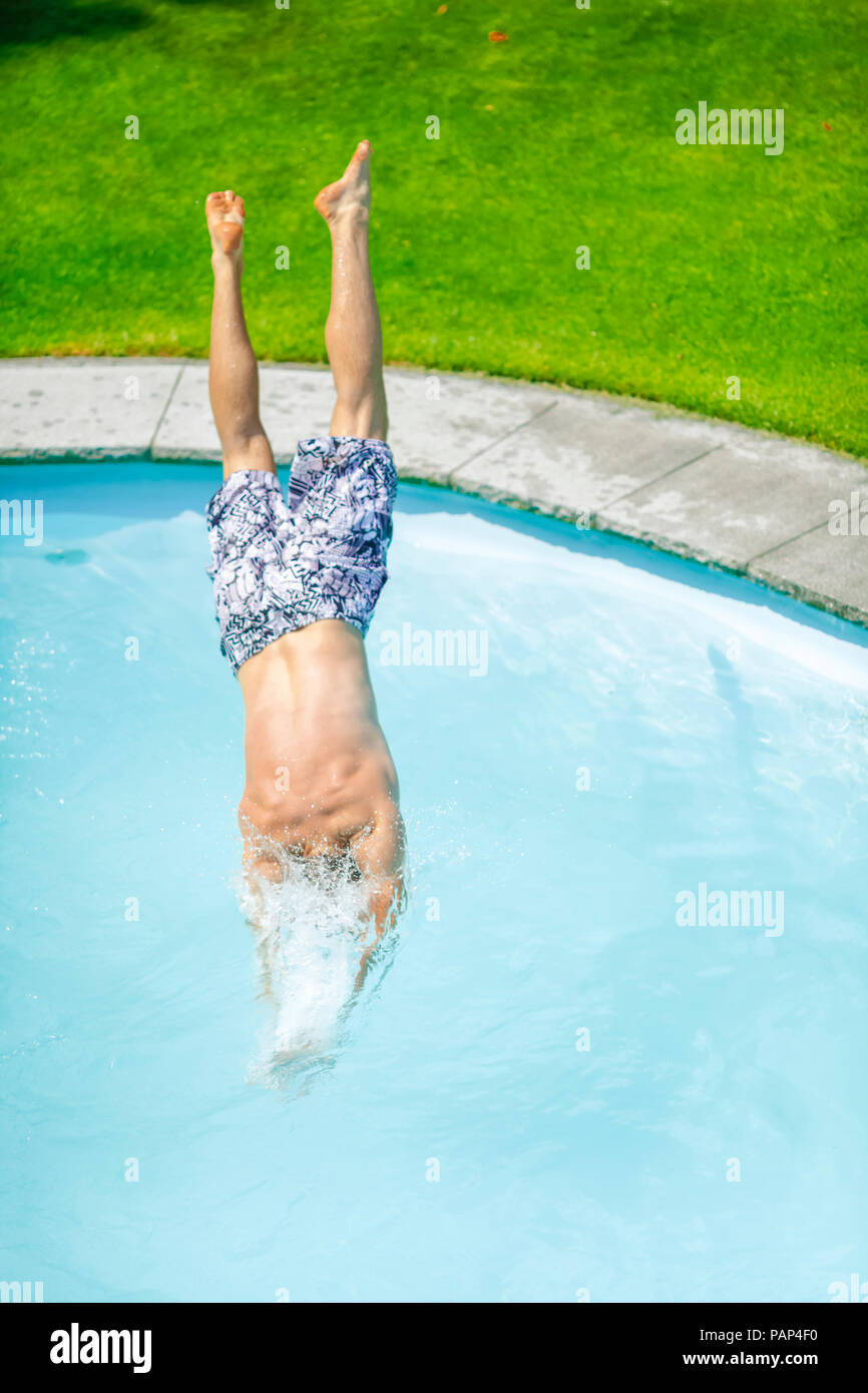 Back view of man jumping into swimming pool Stock Photo