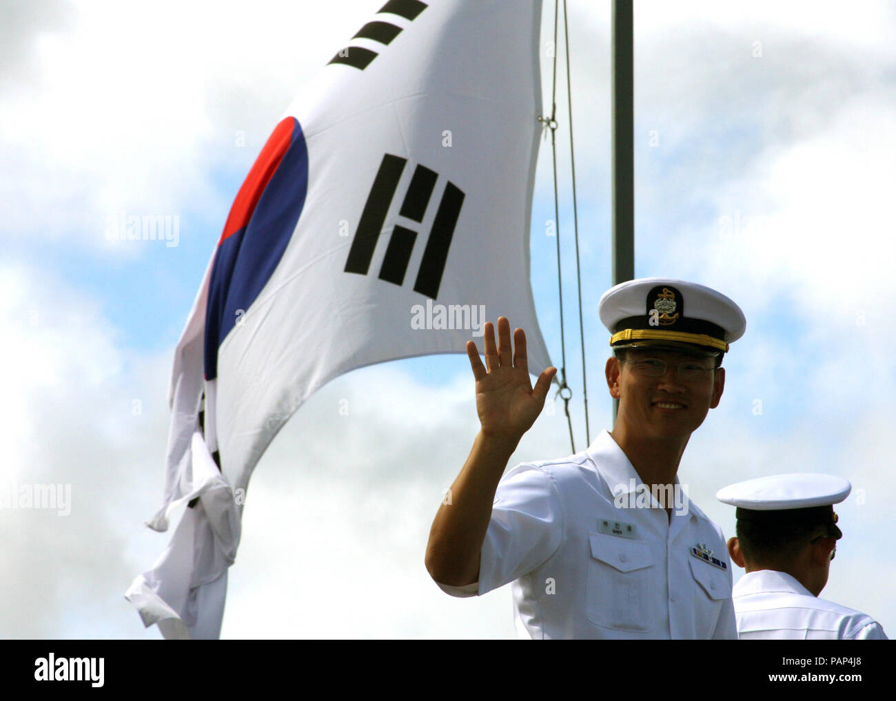 A South Korean navy petty officer. A Republic of Korea sailor, onboard the destroyer ROKS Munmu the Great (DDH 976), waves to onlookers pier side shortly after the ship, along with ROKS Yang Manchoon (DDH 973), arrived at Naval Station Pearl Harbor, Hawaii, June 24, 2008, during the Rim of the Pacific (RIMPAC) 2008 exercise. RIMPAC, the world's largest multinational exercise, is scheduled biennially by the U.S. Pacific Fleet. Participants included the United States, Australia, Canada, Chile, Japan, the Netherlands, Peru, Republic of Korea, Singapore, and the United Kingdom. This year Stock Photo