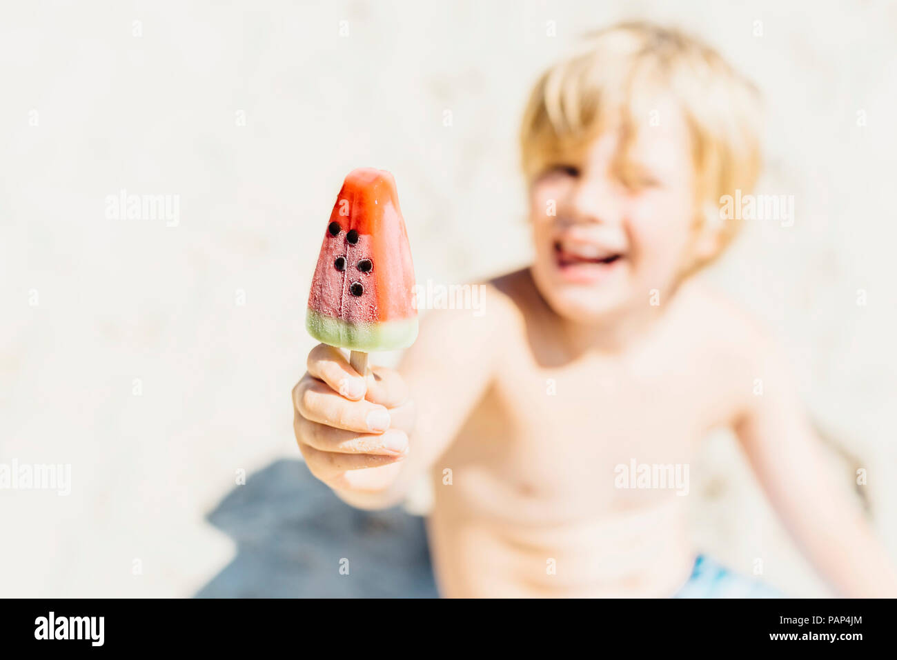 Happy boy holding a watermelon ice lolly on the beach Stock Photo