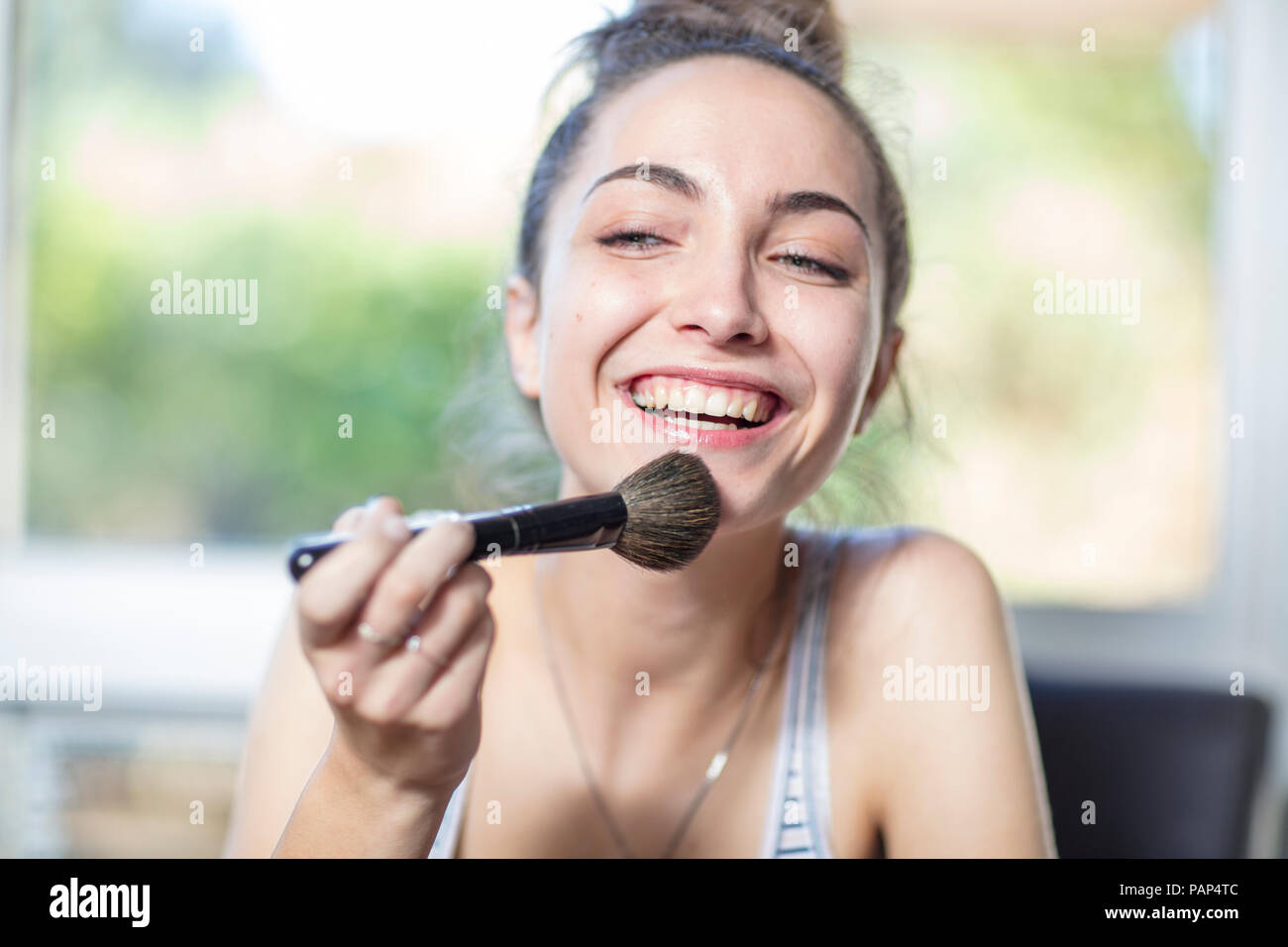 Happy teenage girl applying makeup Stock Photo