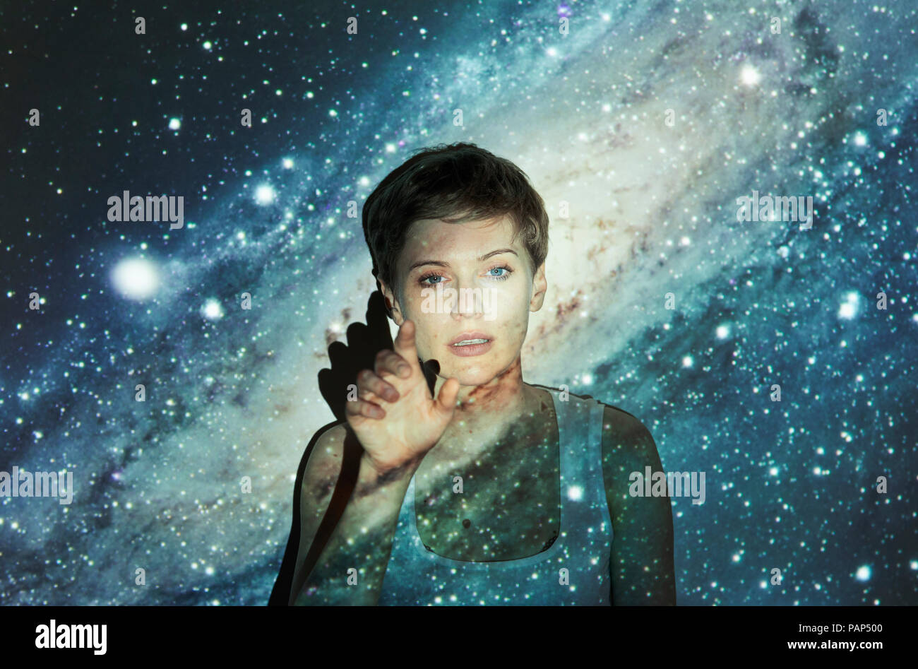 Portrait of blond woman, projection of milky way, imaginary touchscreen
