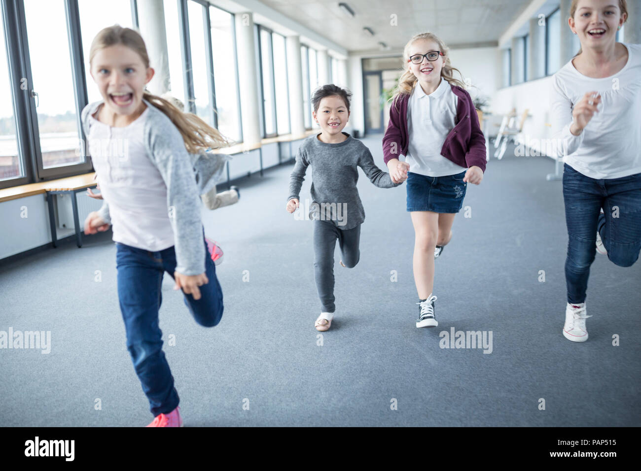 Excited schoolgirls rushing down school corridor Stock Photo