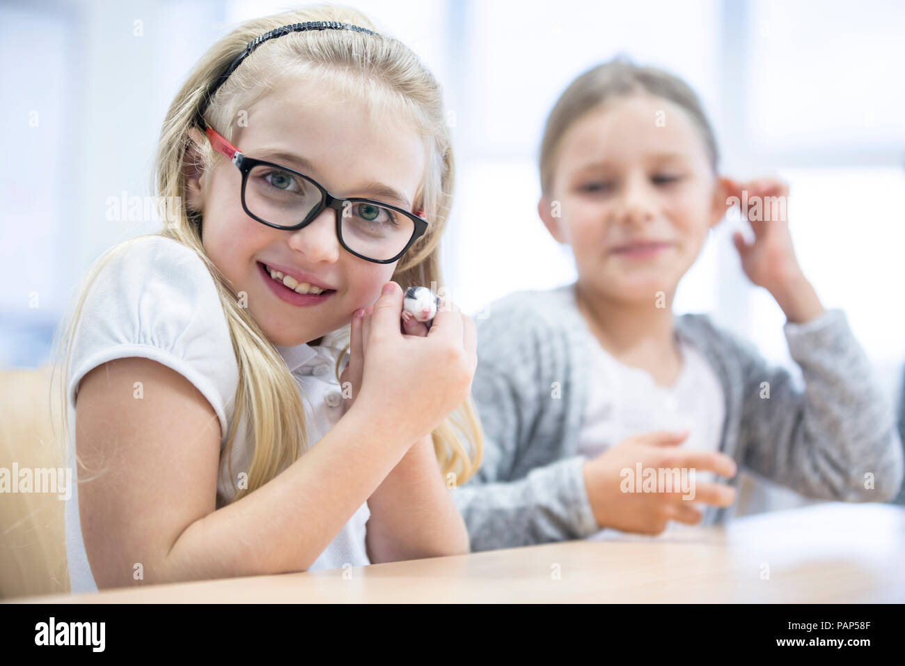 Portrait of smiling schoolgirl in class holding mouse Stock Photo