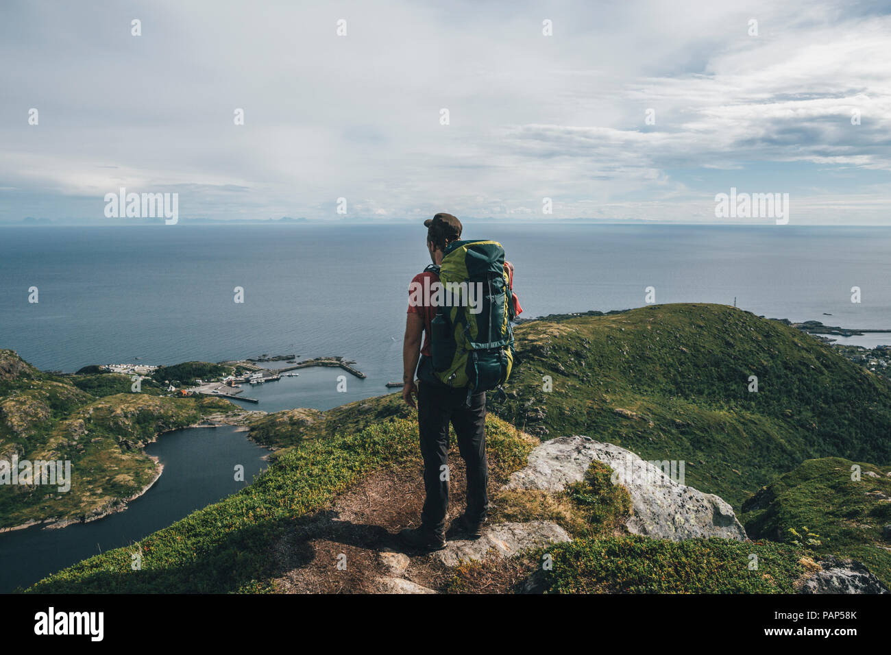 Norway,, Lofoten, Moskenesoy, Backpacker standing on cliff, looking to the Atlantic Ocean Stock Photo