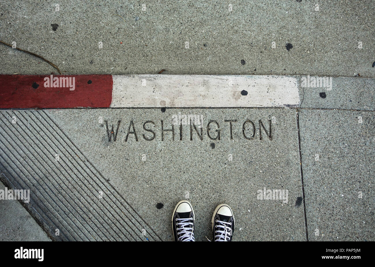 A pedestrian's feet and tennis shoes, looking down on Washington Street in downtown San Francisco, California - USA Stock Photo