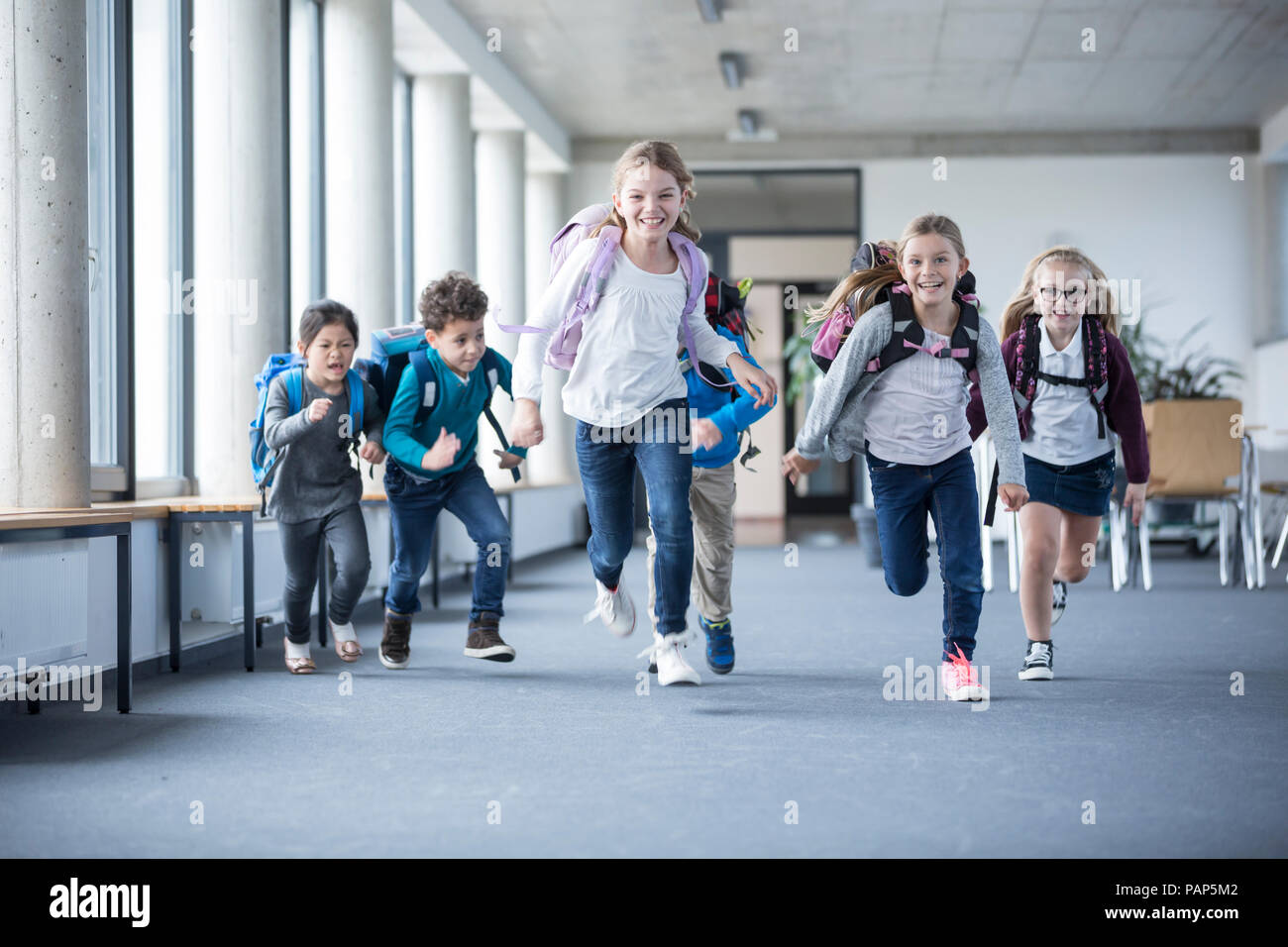 Excited pupils rushing down school corridor Stock Photo