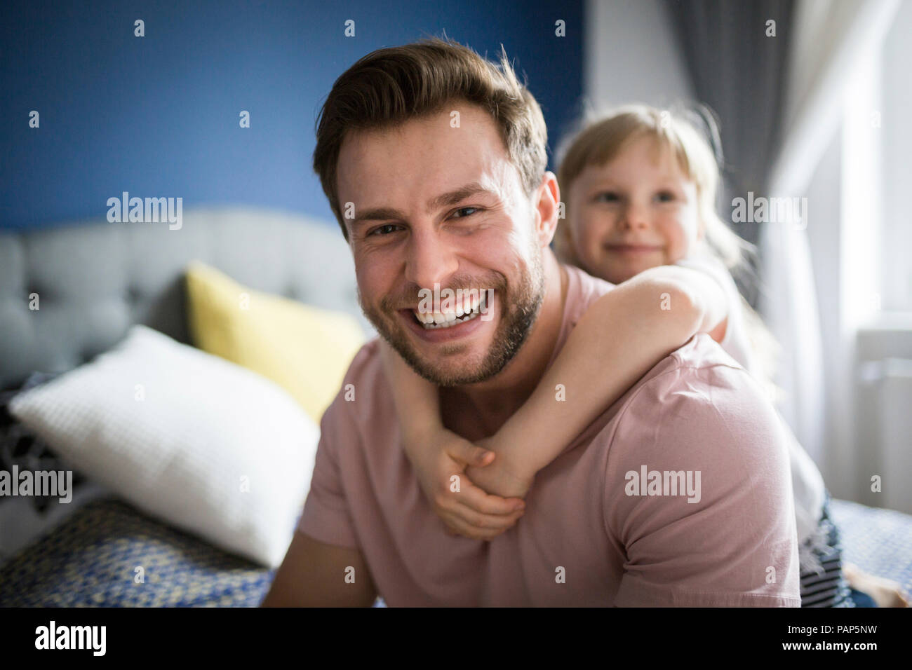 Happy father and daughter sitting on bed, embracing Stock Photo