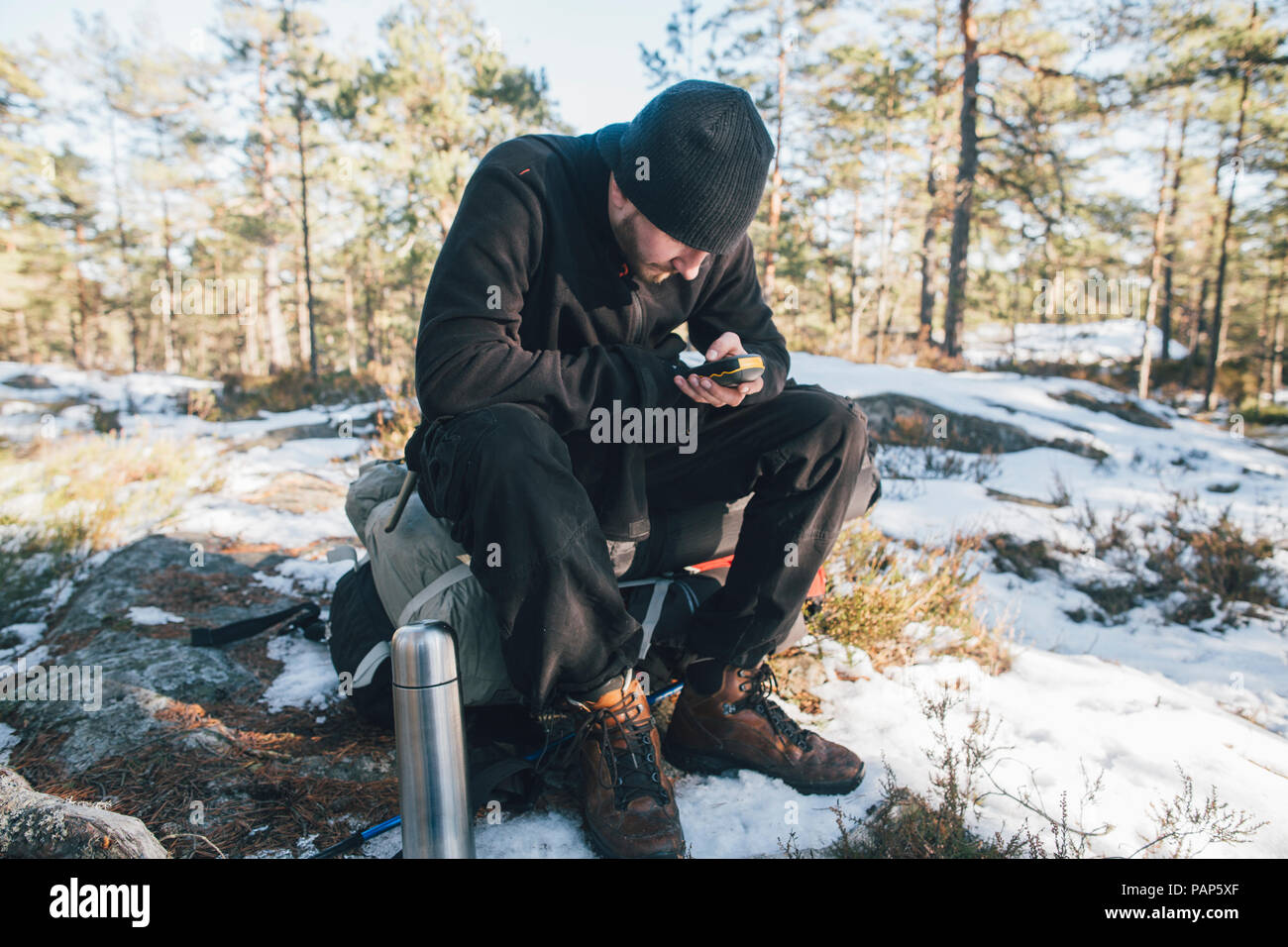 Sweden, Sodermanland, backpacker resting in remote landscape in winter using GPS tracker Stock Photo