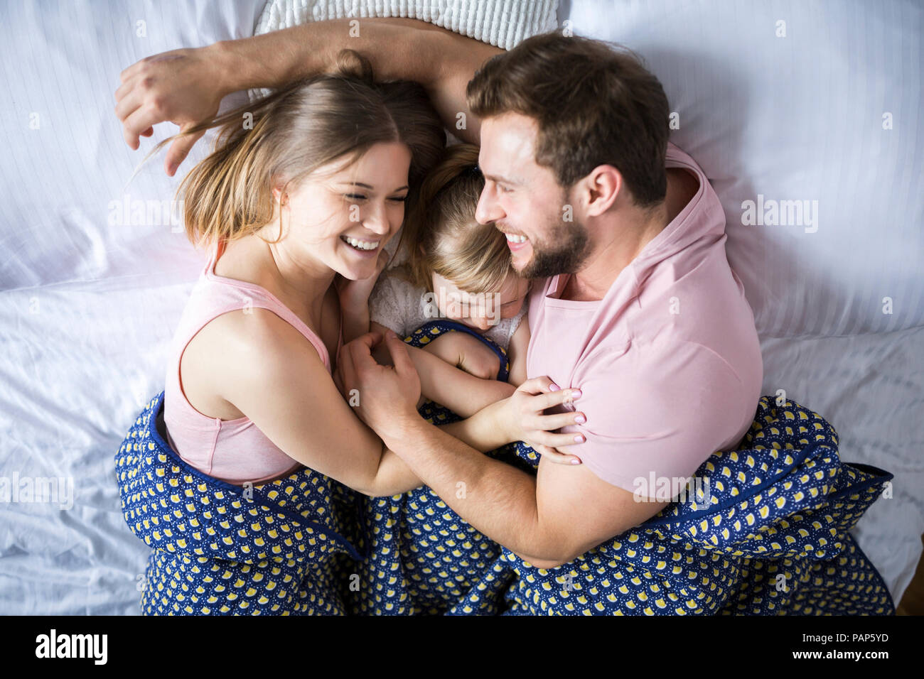 Happy family lying in bed, cuddling Stock Photo