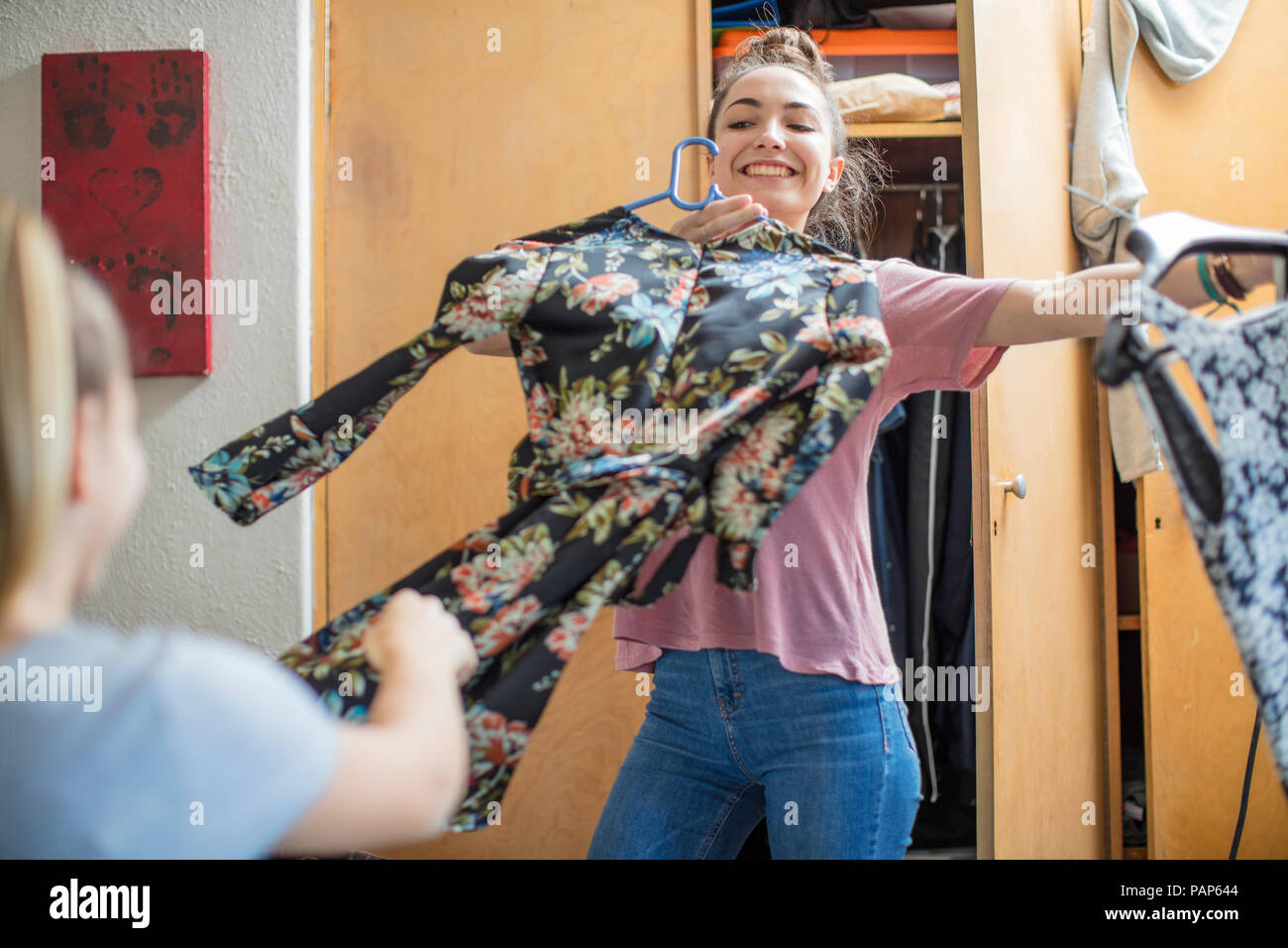 Smiling teenage girl presenting clothes to her friend Stock Photo