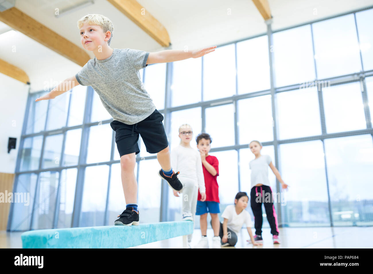 Schoolboy balancing on balance beam in gym class Stock Photo