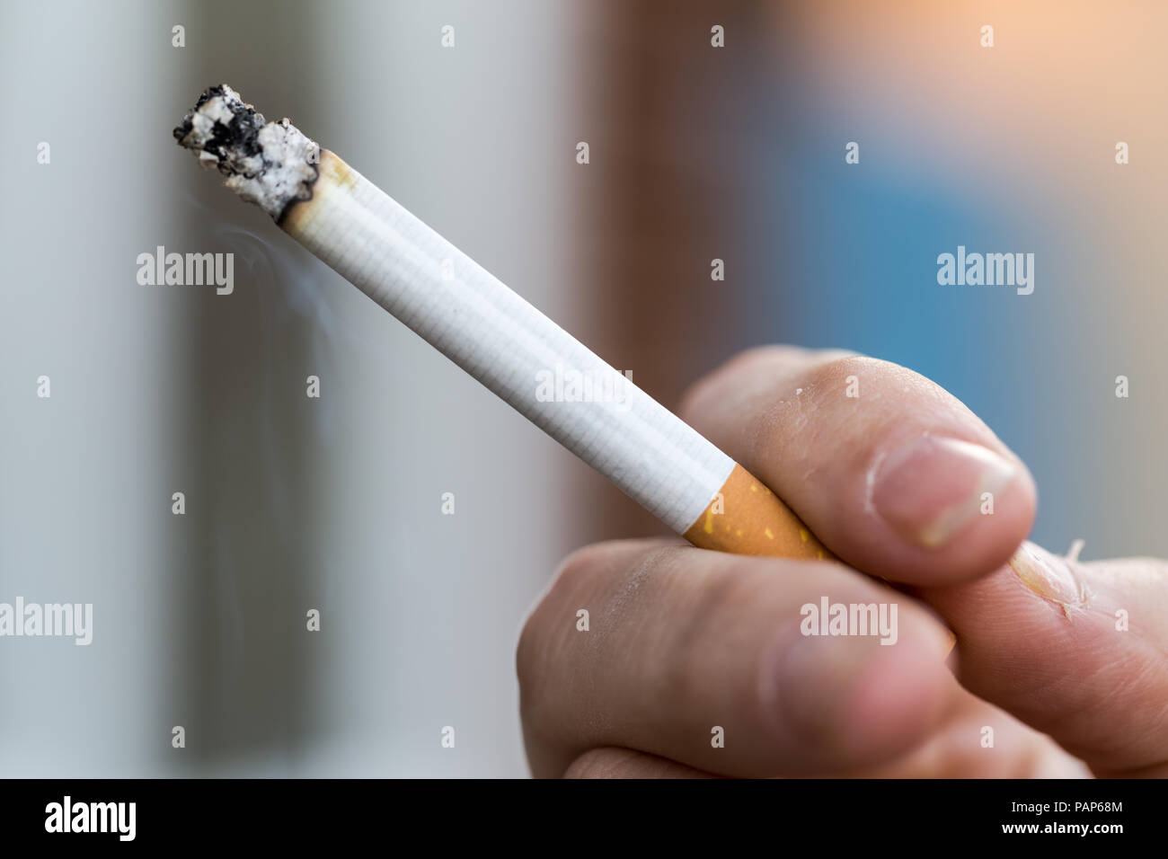 Man smoking a king size cigarette, with ash and smoke Stock Photo