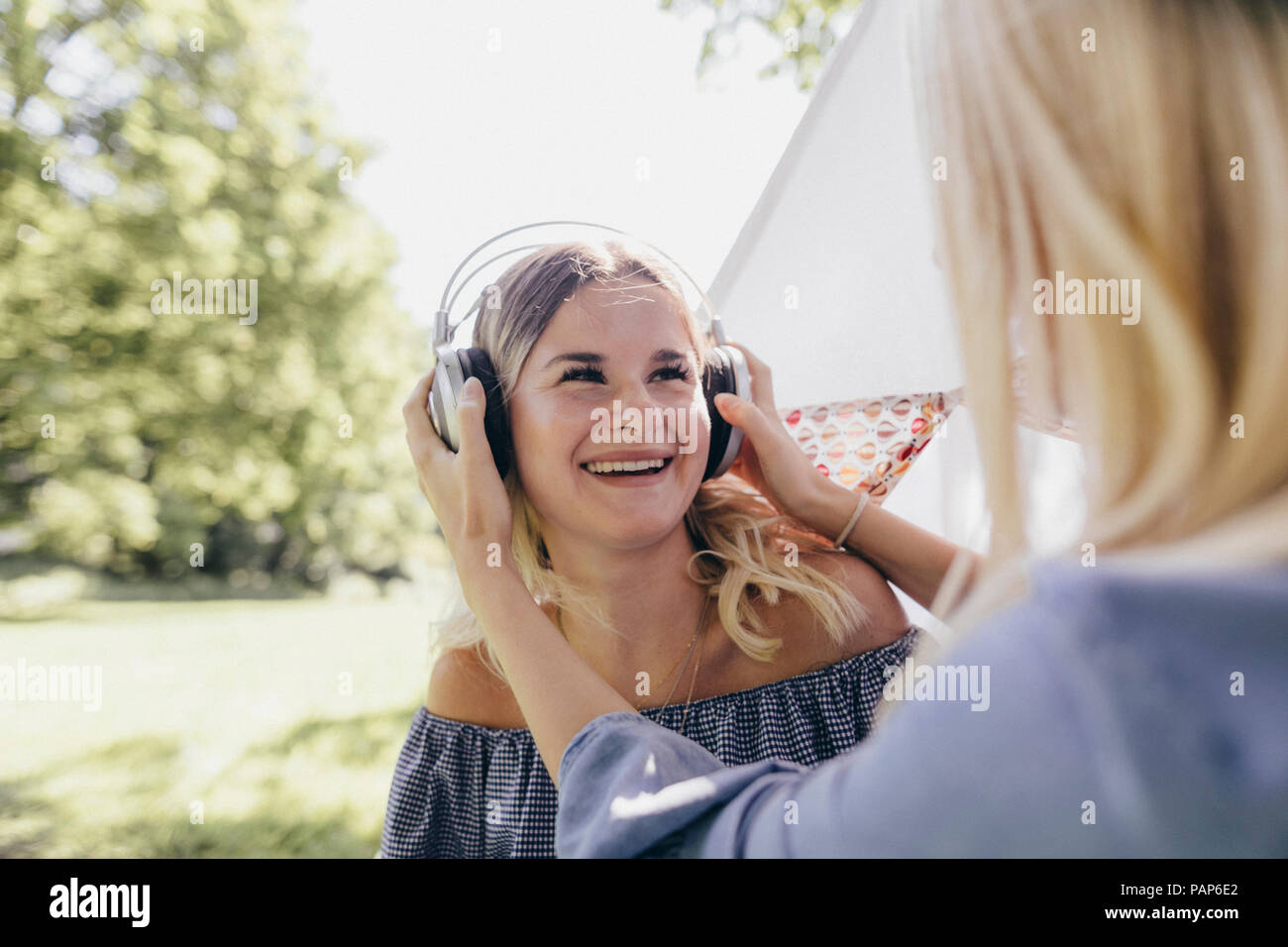 Two happy young women with headphones in a park Stock Photo - Alamy