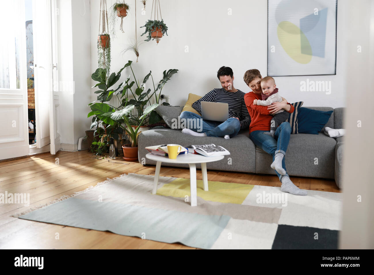 Family sitting on couch, using laptop Stock Photo