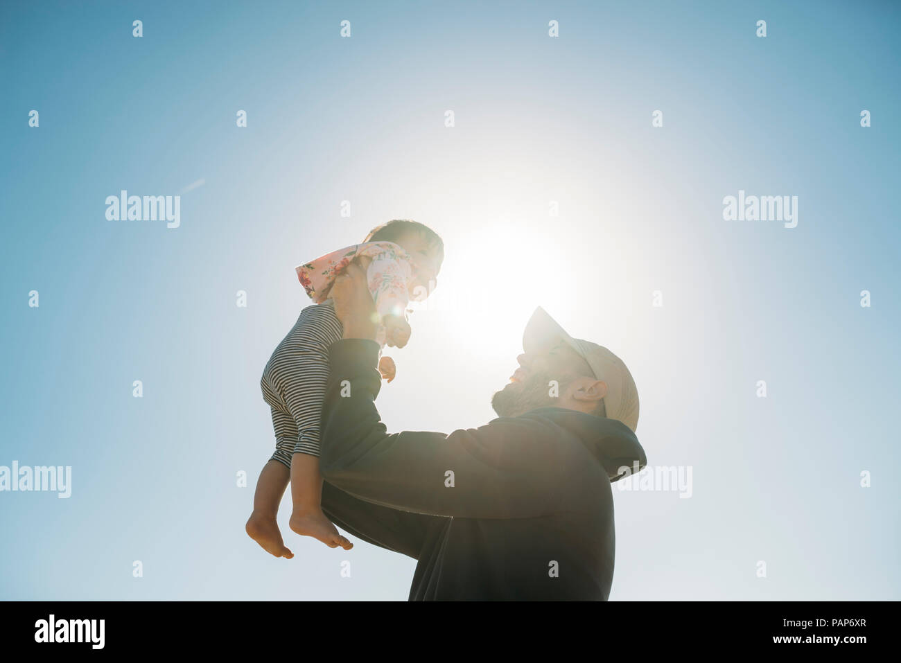 Father holding up baby girl at backlight Stock Photo