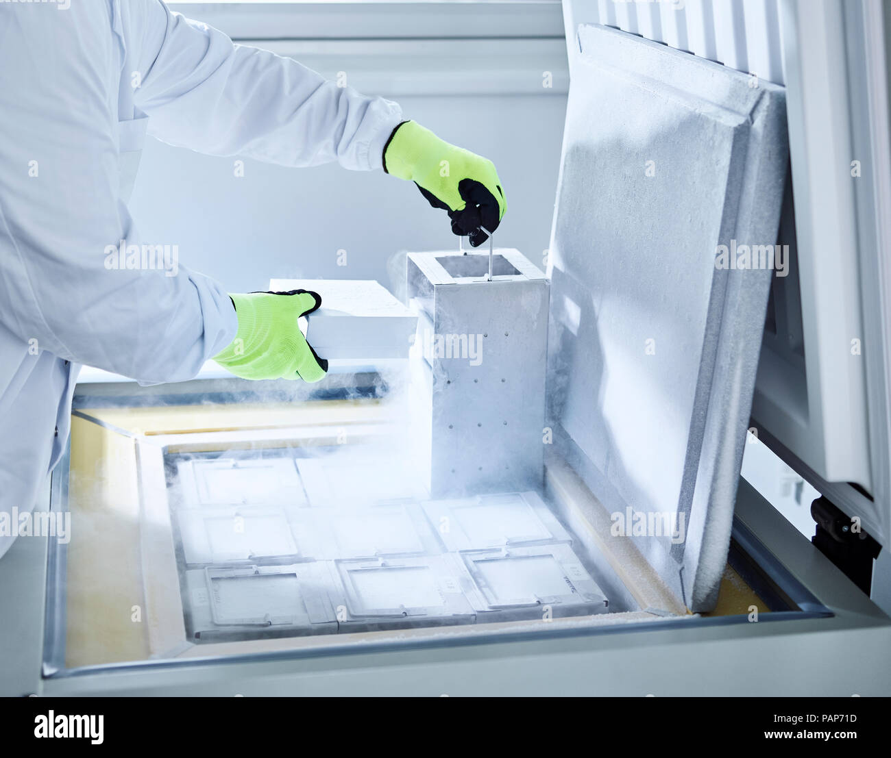 Chemist open upright freezer with gloves Stock Photo