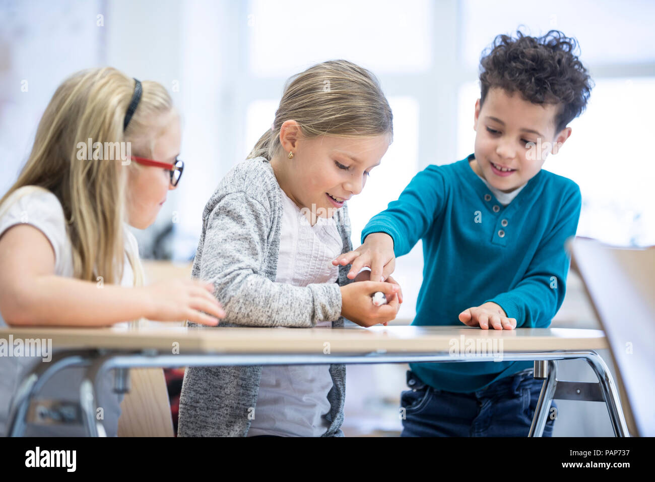 Three pupils in class stroking mouse Stock Photo