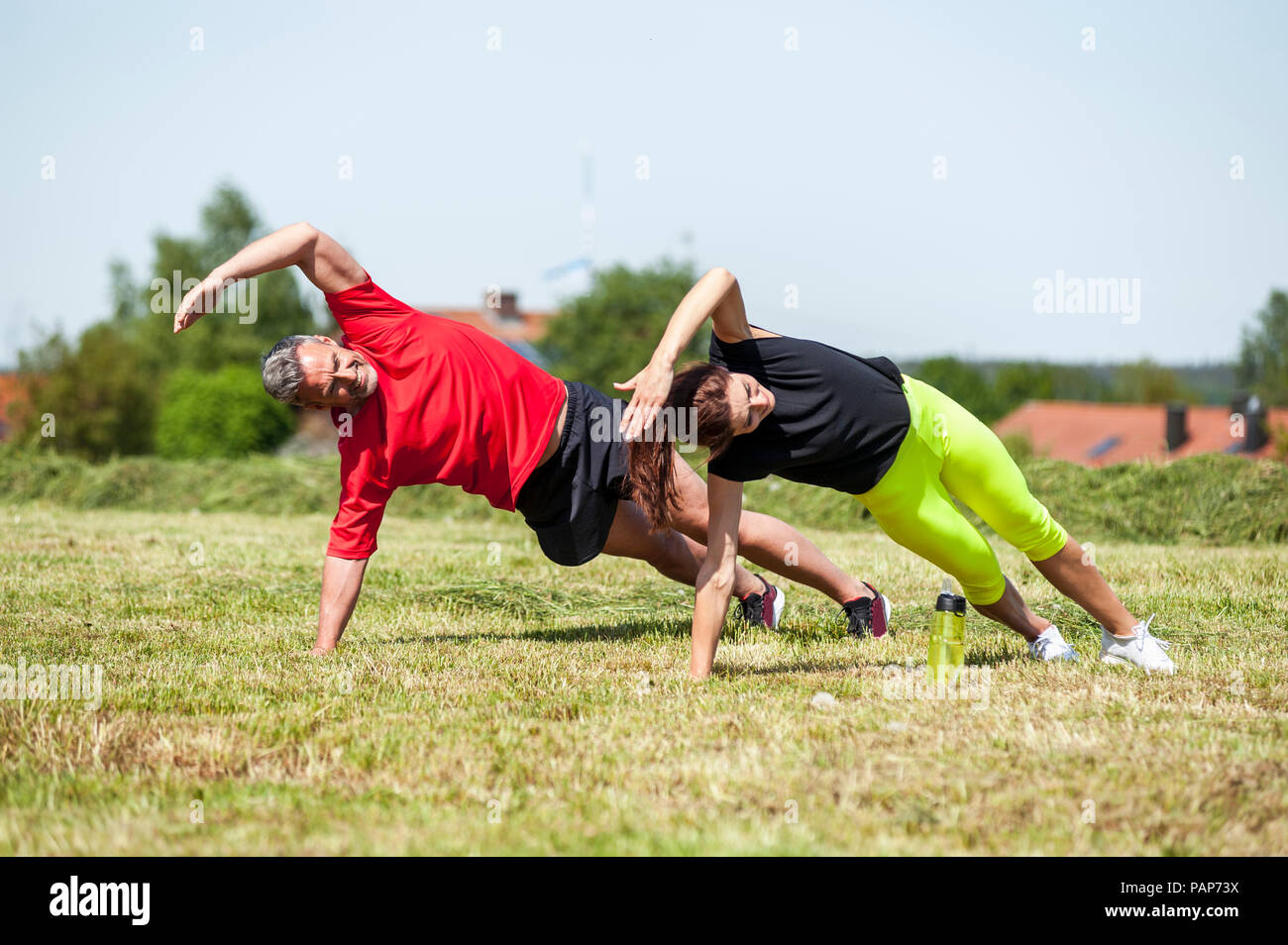 Couple doing side plank exercise on meadow Stock Photo