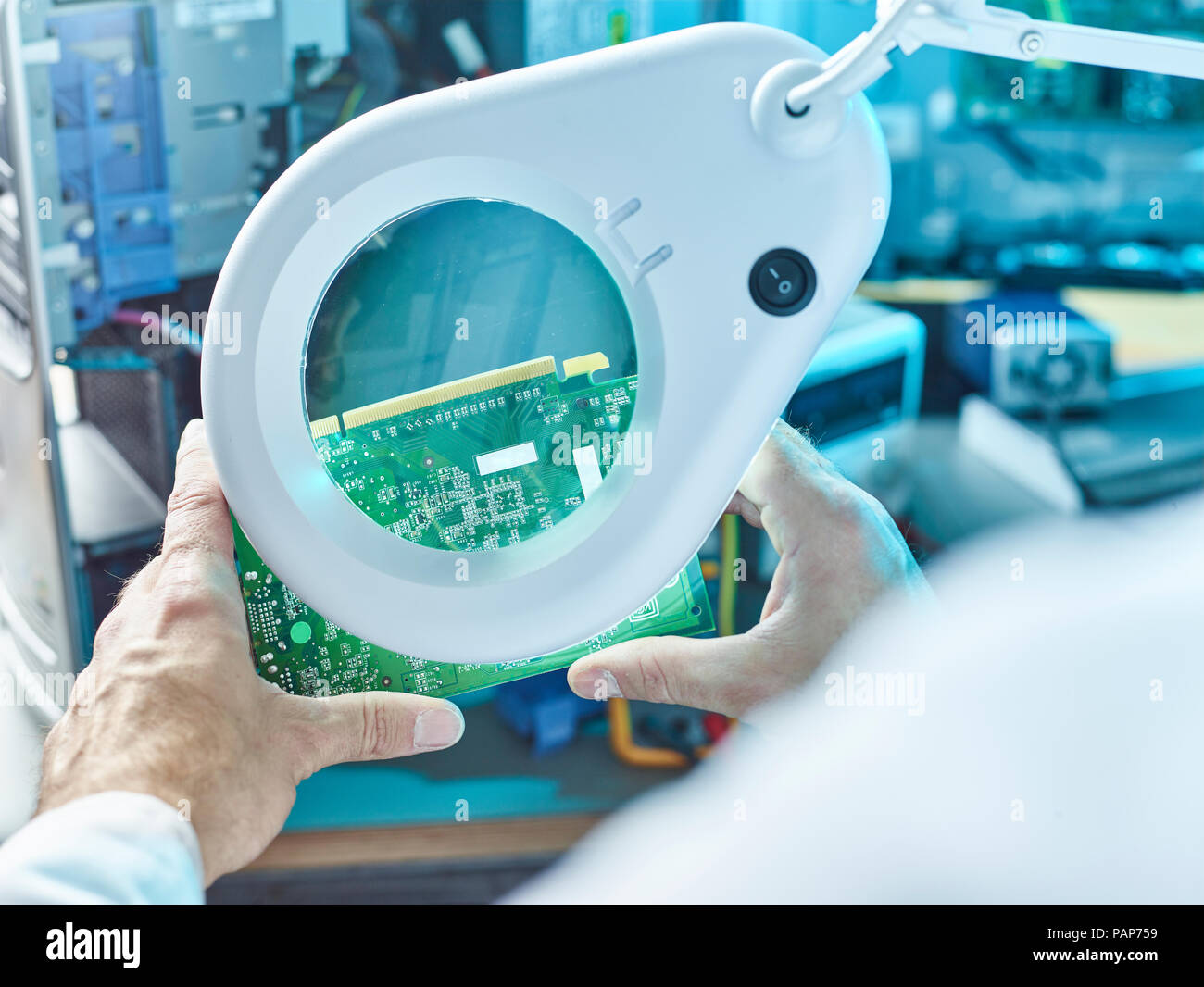 Technician checking circuit board with magnifier Stock Photo