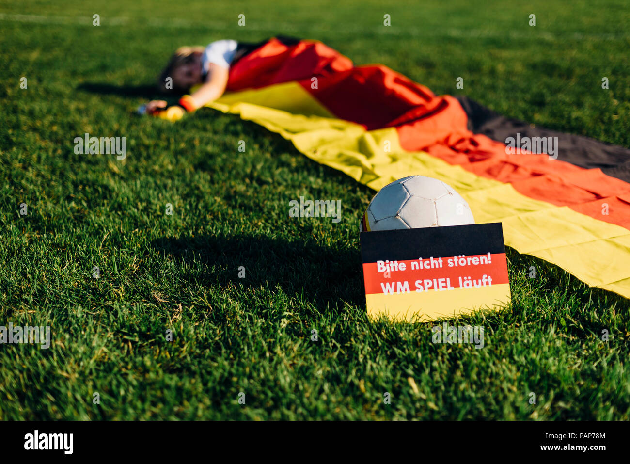 Boy sleeping under German flag with do not disturb sign due to soccer world championship Stock Photo