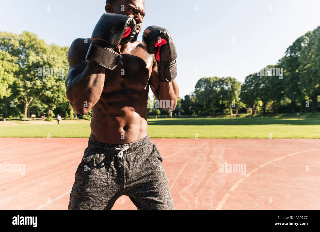 Young Afro-American man training boxing on sports field, outdoors Stock Photo