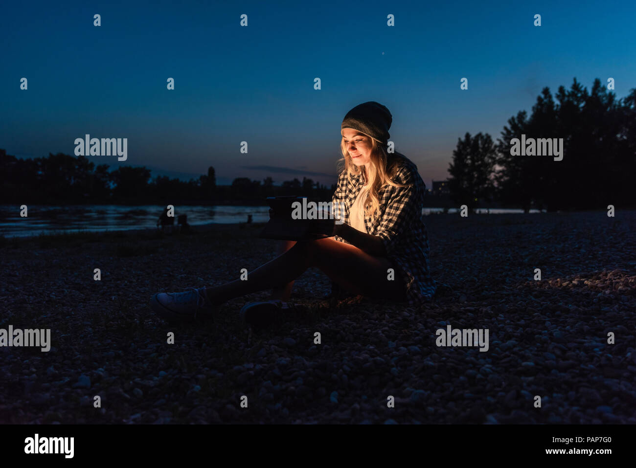 Young woman using smartphone on riverside in the evening Stock Photo