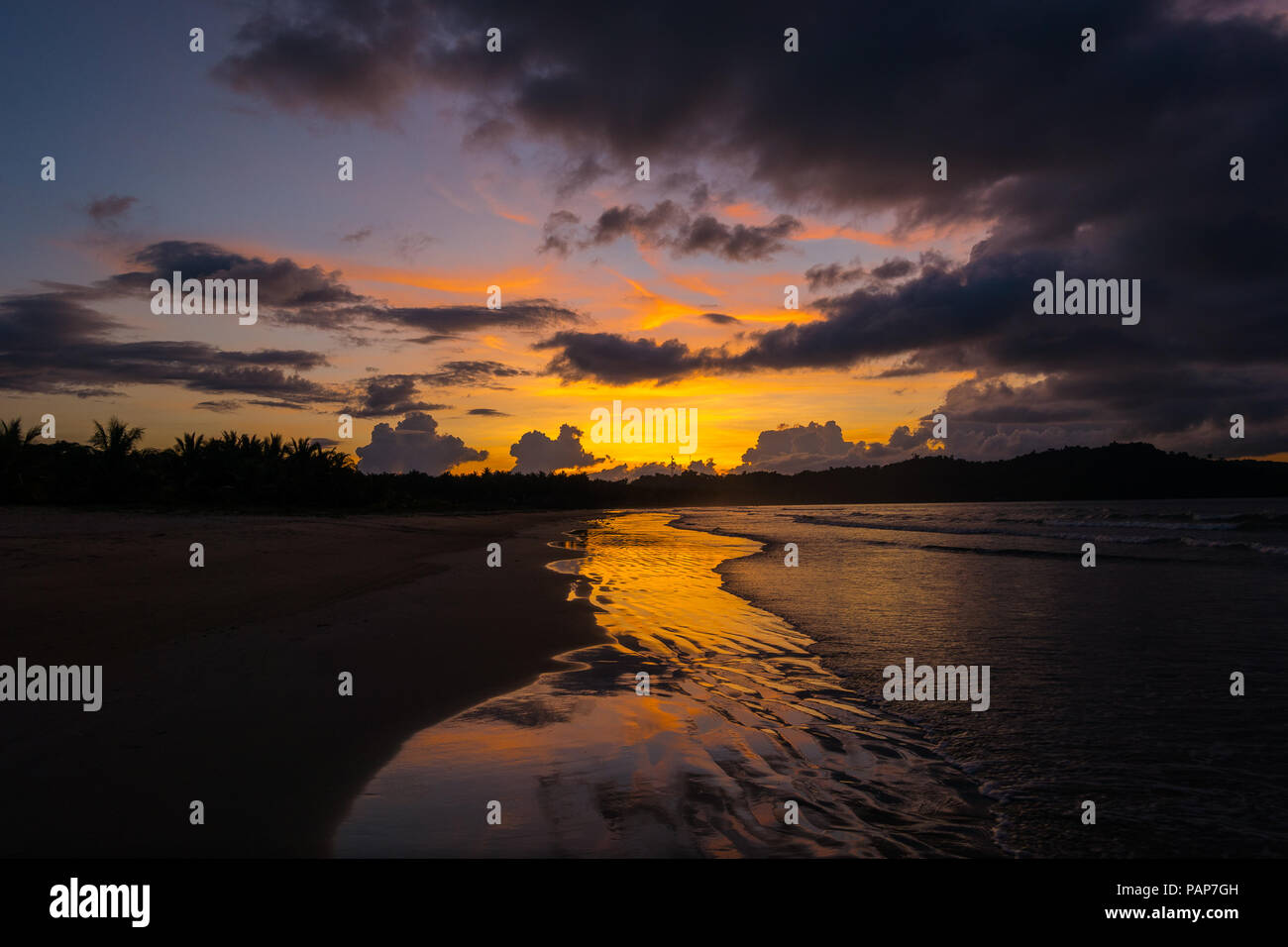 Colorful, cloudy orange sunset hues on Long Beach, San Vicente - Palawan, Philippines Stock Photo